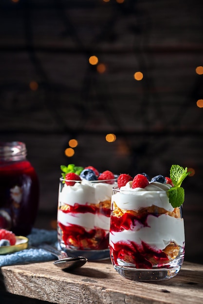 Sur un fond en bois avec des lumières dessert avec des framboises au fromage cottage à la crème et des myrtilles dans ...