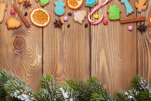 Fond en bois de Noël avec des biscuits et des bonbons de pain d'épice d'épices de sapin de neige