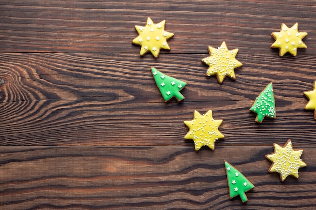 Fond en bois de Noël avec des biscuits ou des pains d'épices en forme d'étoiles et d'arbres avec du glaçage