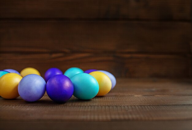 Fond en bois avec des oeufs de Pâques colorés. Concept et joyeuses fêtes de Pâques.