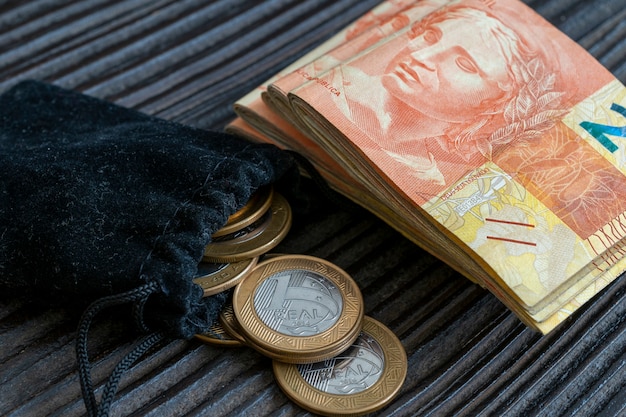 Fond en bois rustique avec pile d'argent et sac à main avec des pièces de monnaie brésiliennes. notion d'économie