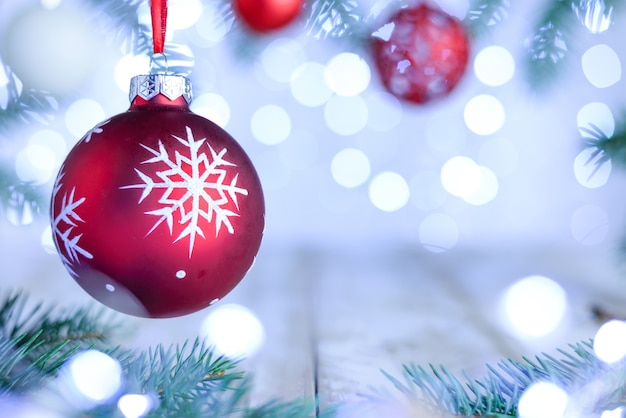Fond de bokeh de Noël avec des branches de pin et une boule ornée rouge.