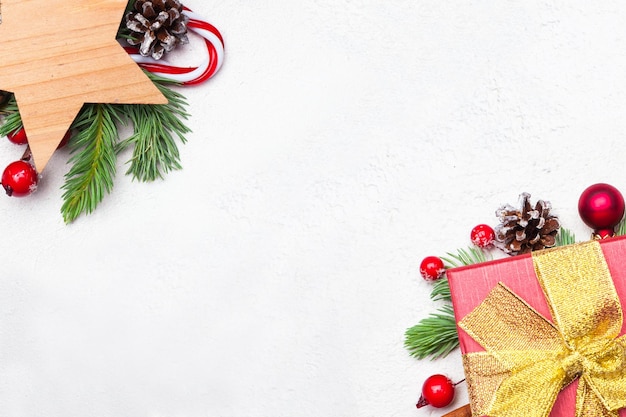 Fond de bordure de Noël avec des décorations de Noël Composition colorée avec cadeau de branche de sapin de Noël vert étoiles baies de houx rouges et boules sur fond blanc