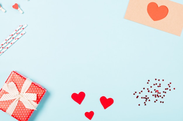 Fond avec cadeau, confettis, coeurs et enveloppe avec espace libre pour le texte sur fond bleu pastel. Concept de la Saint-Valentin.