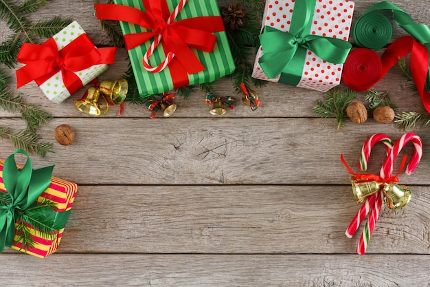 Fond de cadeaux de Noël créatifs. Boîtes à cadeaux colorées faites à la main, brindilles de sapin, ruban de satin, cannes de bonbon et ornements sur table en bois, espace de copie, vue de dessus. Concept de loisirs et de vacances d'hiver