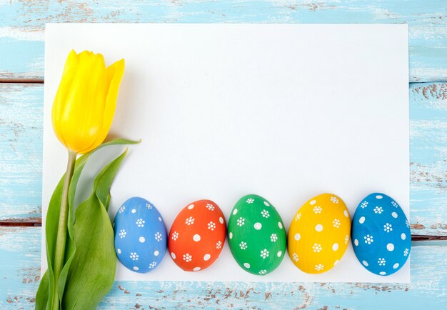 Fond de cadre de Pâques avec des oeufs, fleur de tulipe et papier vierge blanc pour texte