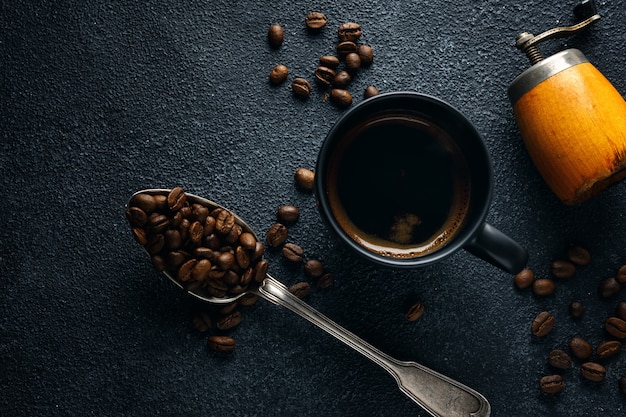 Fond de café avec des grains de café, du café et une cuillère sur fond sombre. Vue d'en-haut. Concept de café.