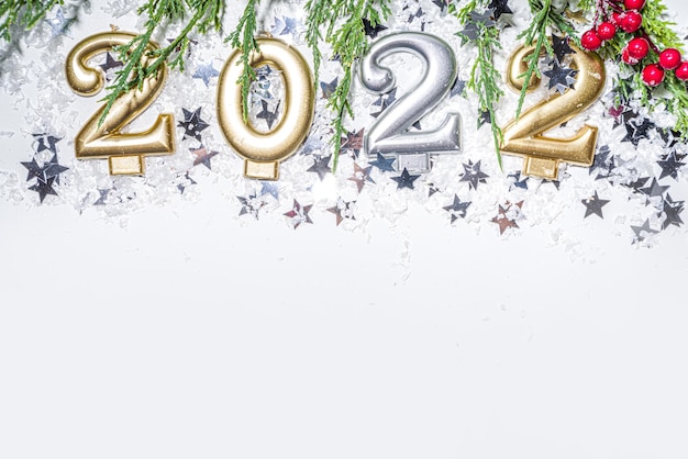Fond de carte de voeux de nouvel an 2022, bannière festive avec bougies de vacances 2022, décor d'étoiles argentées, branches d'arbres de Noël et neige artificielle