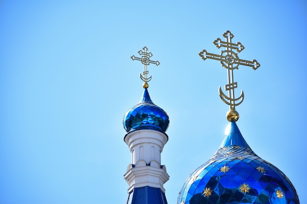 Sur fond de ciel bleu clair, deux dômes d'une église chrétienne ou d'un monastère de différentes tailles, avec des croix en haut