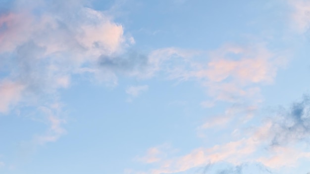 Fond de ciel bleu avec des nuages roses pâles au coucher du soleil