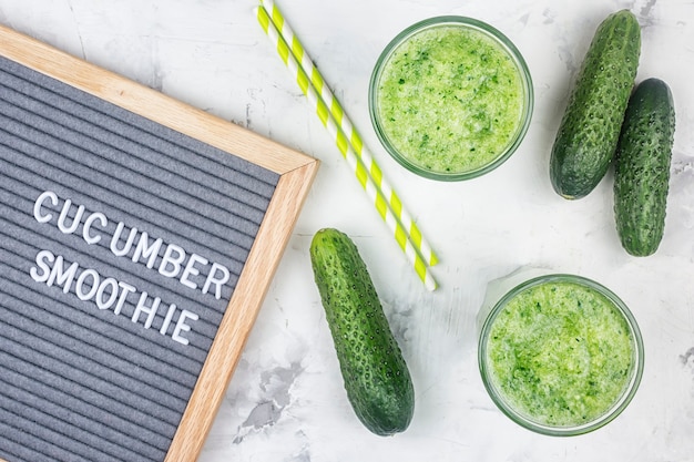 Sur fond clair, deux verres de jus vert fraîchement pressé.