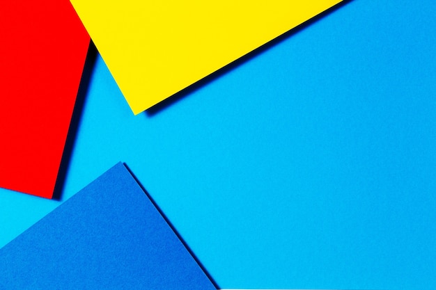 Fond de composition à plat de géométrie de papiers de couleur abstraite avec des tons de couleur bleu jaune et rouge