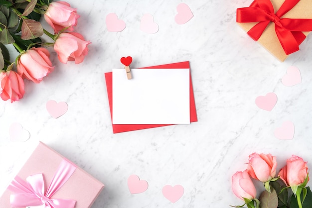 Fond de concept de design Saint Valentin avec fleur rose rose, boîte-cadeau et carte sur fond blanc en marbre