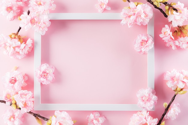 Photo fond de couleurs rose pastel avec cadre photo et fleurs de fleurs à plat.