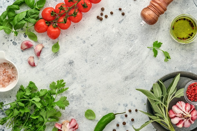 Fond de cuisson des aliments. Safran frais, ail, coriandre, basilic, tomates cerises, poivrons et huile d'olive, épices, herbes et légumes sur une table en ardoise gris clair. Vue de dessus des ingrédients alimentaires.