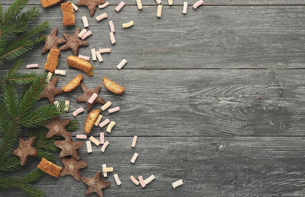 Fond de cuisson de Noël. Biscuits au pain d'épice et cadre de branches de sapin pour la recette de pâtisserie du nouvel an, maquette. Vue de dessus avec espace de copie sur une table en bois rustique