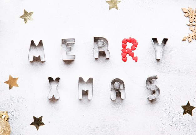 Fond de cuisson de Noël ou du Nouvel An avec des formes de cuisson de lettre pour les biscuits de pain d'épice inscription Joyeux Noël vue de dessus de table grise