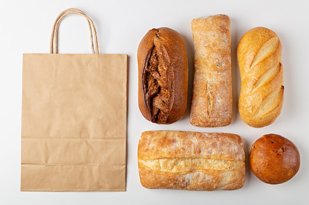 Photo fond de cuisson avec sac en papier jetable écologique et miches de pain vue de dessus sur fond gris avec maquette