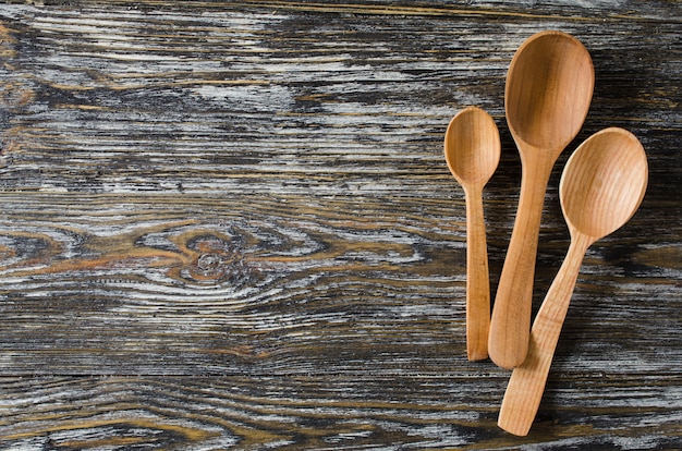 Fond culinaire avec des cuillères rustiques sur une table en bois vintage.