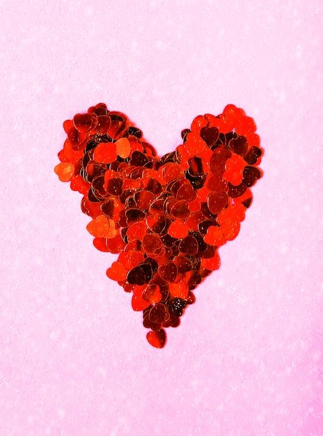 Fond décoratif de la Saint-Valentin avec coeur fait de guirlandes. Effet de chute de neige sur fond rose tendre.