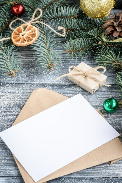 Fond de décoration de Noël ou du nouvel an avec des branches de sapin, des cônes, des boules, des guimauves sur une planche en bois grise.