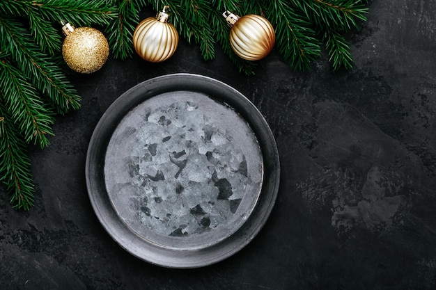 Fond de dîner de Noël avec assiette vide et décor doré sur table sombre vue de dessus espace copie