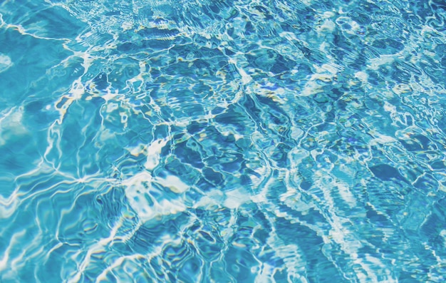 Fond d'eau bleue dans la piscine avec vague d'eau d'ondulation de réflexion du soleil dans l'eau claire de la piscine