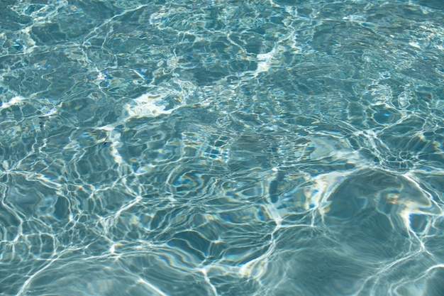 Fond d'eau bleue dans la piscine avec vague d'eau d'ondulation de réflexion du soleil dans l'eau claire de la piscine