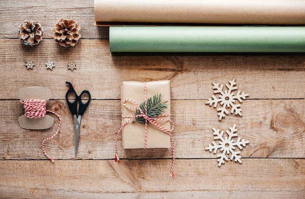 Photo fond d'emballage cadeau de noël avec du papier kraft, de la corde de jute, des ciseaux et des branches de pin