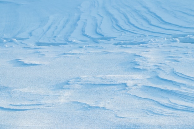 Photo fond enneigé, surface enneigée de la terre après un blizzard le matin au soleil avec des couches distinctes de neige