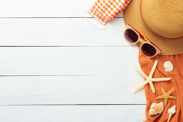 Fond d'été avec accessoires de plage - chapeau de paille, lunettes de soleil, serviette et masque pour éviter la covid-19