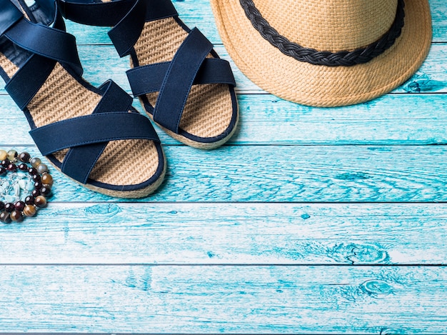 Fond d&#39;été Chapeau de paille Bracelets Sandales Lunettes de soleil Coquillages sur une table bleue