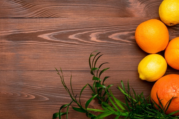Fond d'été de citrons, d'oranges et de palmiers sur une surface en bois