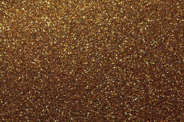 Fond étincelant doré foncé de petits paillettes, gros plan. Toile de fond brillante.