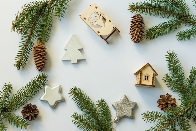 Fond Festif Du Nouvel An Avec Des Cônes Et Des Branches Vertes, Des étoiles Argentées, Des Traîneaux En Bois Et Une Maison De Jouets. Disposition à Plat. Vue De Dessus.