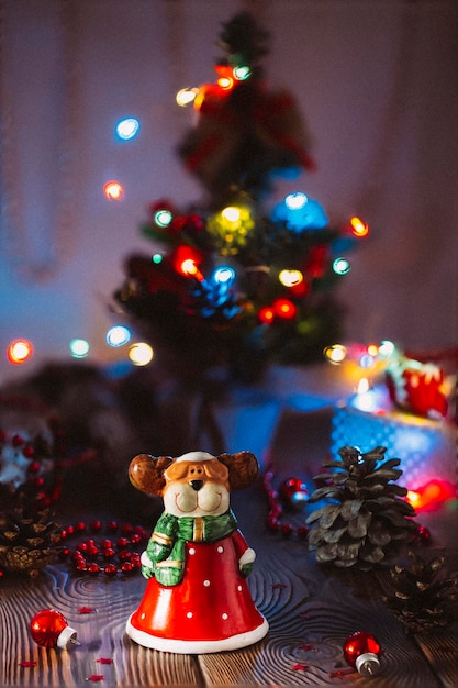 Fond festif de Noël avec un cerf jouet déguisé en arbre de Noël du Père Noël décoré d'un décor avec des lumières dorées fond festif sur une table en bois gros plan