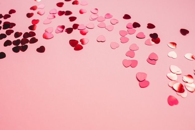 fond festif rouge et rose avec des confettis en forme de coeur rouge.