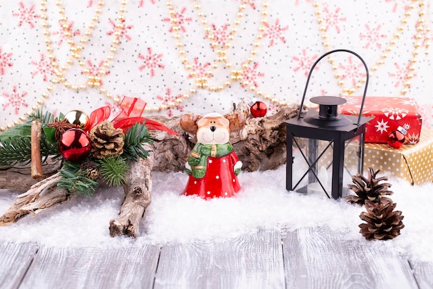 Fond de fête de Noël avec un élan jouet dans un costume de Père Noël et une lanterne un arbre de Noël avec des cônes d'oranges séchées sur la neige sur une table grise en bois placement de l'espace libre de copie
