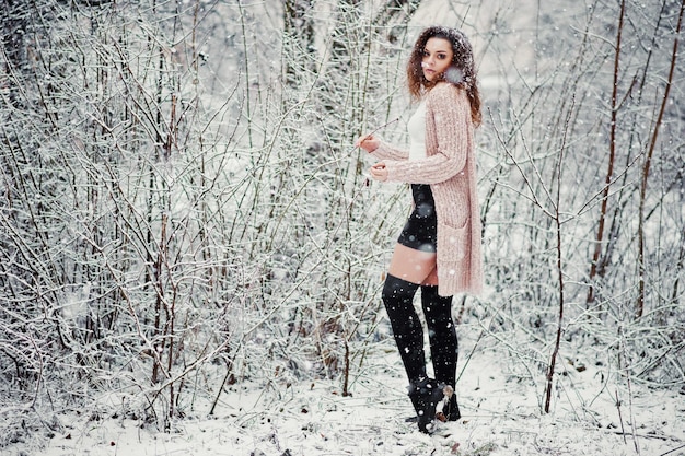 Fond de fille brune bouclée chute de neige porter sur pull tricoté chaud mini jupe noire et bas de laine Modèle en hiver Portrait de mode par temps neigeux Instagram photo tonique