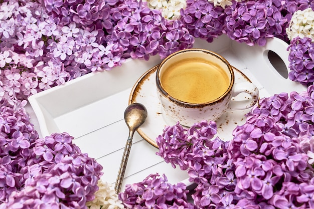 Fond de fleurs lilas avec une tasse de café au milieu avec espace de copie.