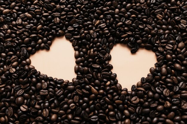 Fond avec une gamme de grains de café secs avec deux formes de coeur.