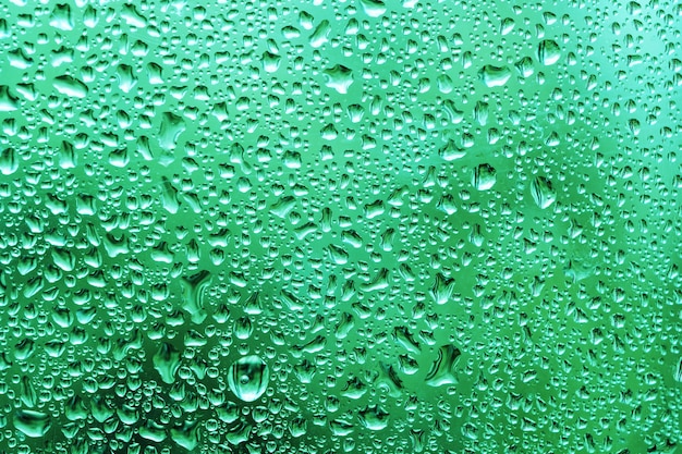 fond de gouttes d'eau sur la fenêtre après la pluie d'été avec un feuillage vert derrière une vitre