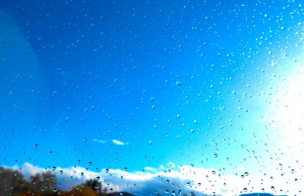 fond gouttes de pluie sur la fenêtre avec la lumière naturelle du ciel bleu