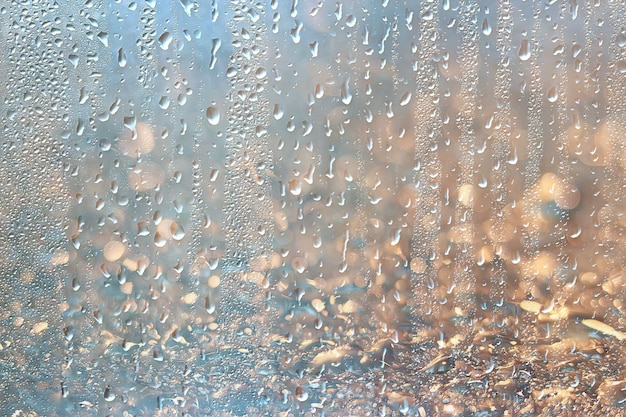 fond gouttes de verre humide automne dans le parc / vue sur le paysage dans le parc d'automne depuis une fenêtre humide, le concept de temps pluvieux un jour d'automne