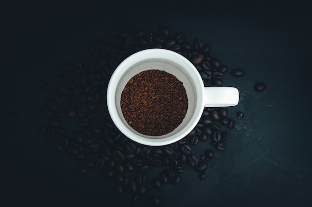 Fond de grains de café et une tasse de café cru, la vue de dessus