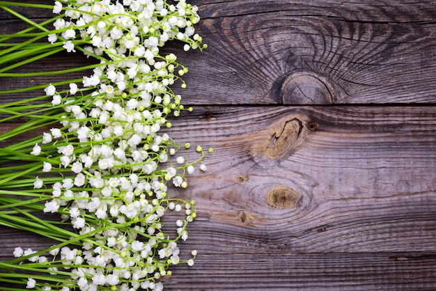 Fond gris en bois avec des fleurs fraîches Lys de la vallée