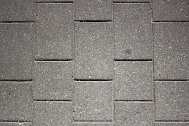 Fond gris d'un pavé de briquesContexte d'un bloc de carreaux de pierre grisesSurface d'une brique griseTexture de dalle de pavé de pierreRoutedalle de béton