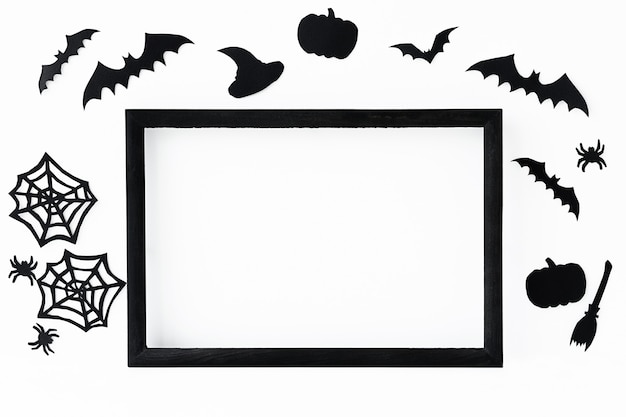 Fond d'Halloween avec cadre noir et accessoires en papier noir pour des vacances sur une surface grise