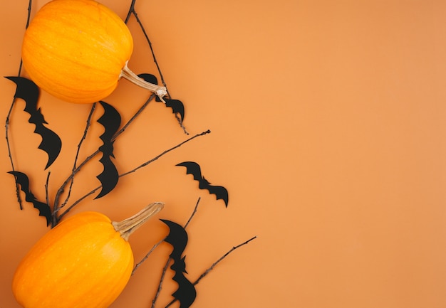 Fond d'Halloween avec des citrouilles, des chauves-souris, des décorations sur fond orange. Maquette de carte d'invitation de fête d'Halloween avec espace de copie.