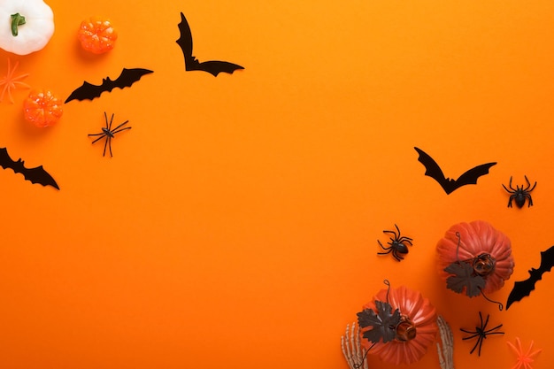 Fond d'Halloween orange Troupeau de chauves-souris noires squelette de citrouille araignée et feuilles pour Halloween Silhouettes de chauve-souris en papier noir sur fond orange Décoration d'automne Concept d'Halloween Vue de dessus